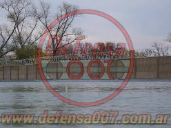 Instalación de concertina helicoidal cruzada sobre muro premoldeado. Delante piletones de tratamiento de agua. Parque logístico.