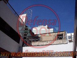 Instalación de concertina plana de 65 cm sobre medianera en patio trasero de edificio.