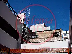 Instalación de concertina plana de 65 cm sobre medianera en patio trasero de edificio.